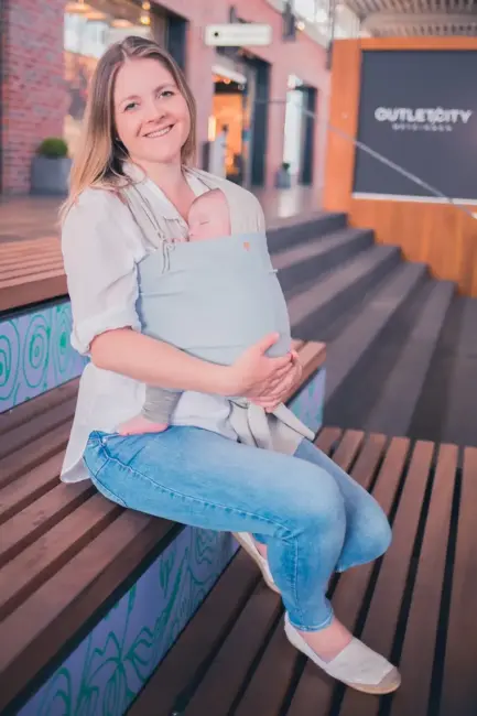 Isabel, zertifizierte Trageberaterin in Tübingen, sitzt mit einem Baby im Tragetuch, demonstriert komfortables Tragen.